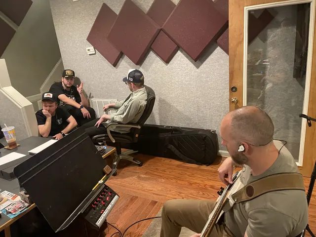 Bass player tracking while musicians talk through the song behind him