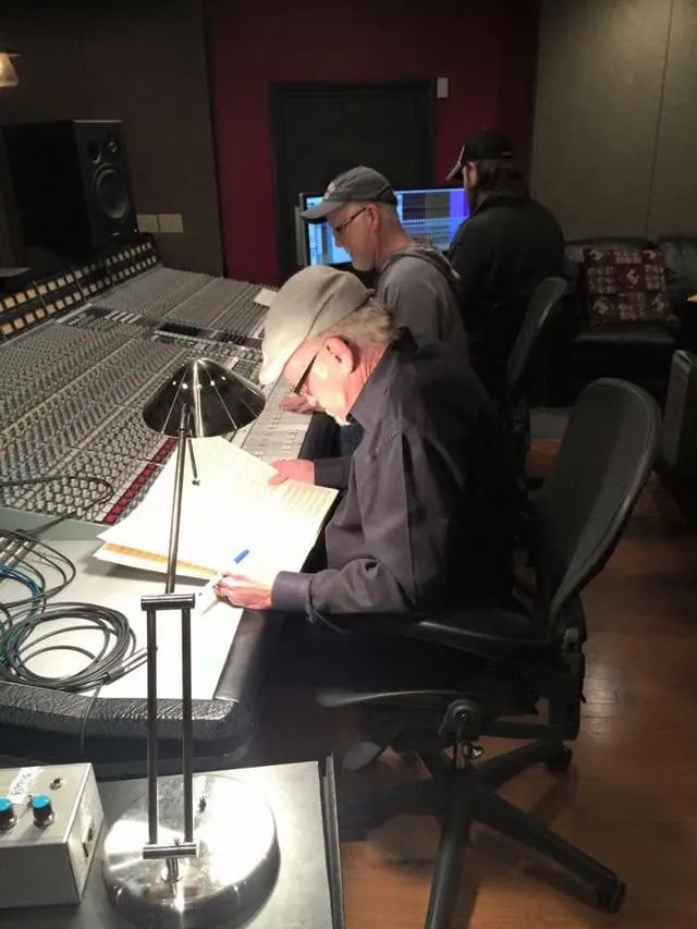 Engineer making notes at the large-format console while others work behind
