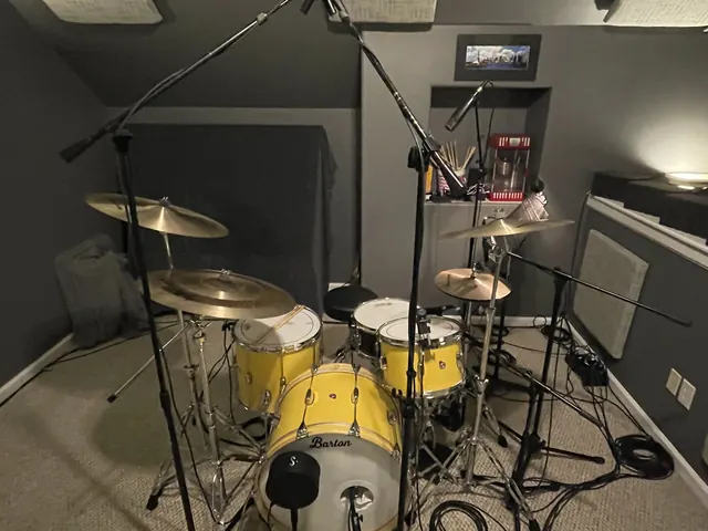 Wide view of the drum room with the yellow house kit and cymbals set up