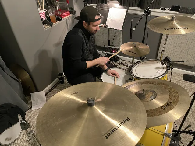 Drummer playing the house kit, seen over the cymbals