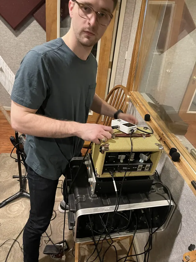 Guitarist dialing in his amp head in the live room
