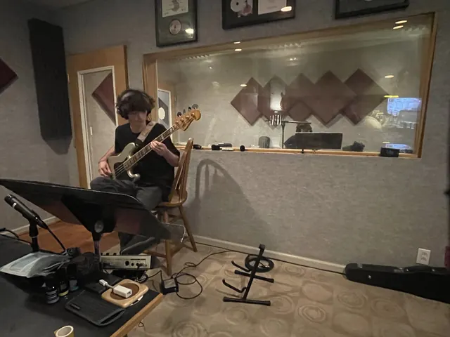 Guitarist playing in the live room by the control room window