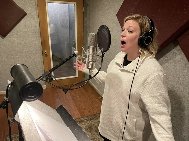 Female vocalist belting a note at the microphone in the vocal booth