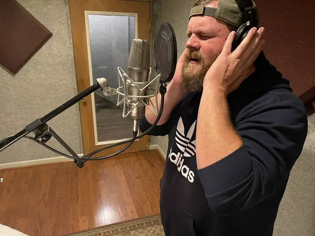 Male vocalist holding his headphones while singing in the vocal booth